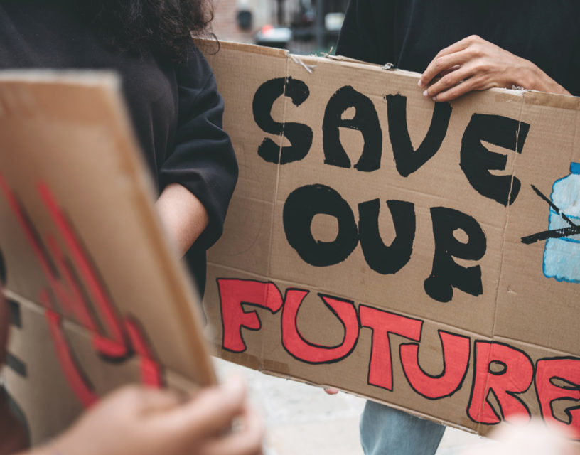 Människor håller handmålade skyltar, på en skylt texten "Save our future".