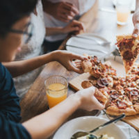 Ihmiset syövät yhdessä pizzaa.