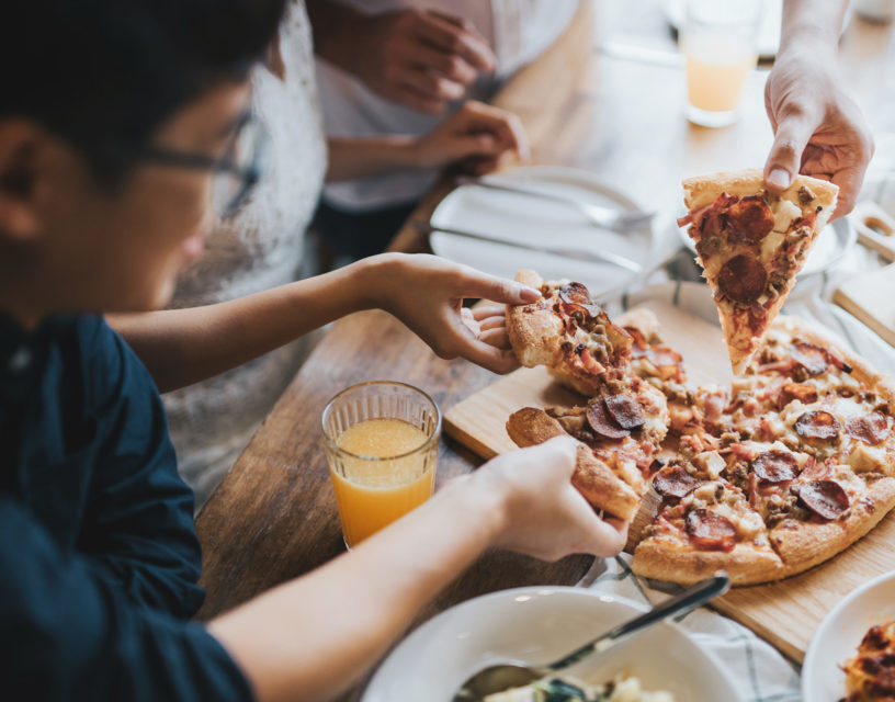 Ihmiset syövät yhdessä pizzaa.