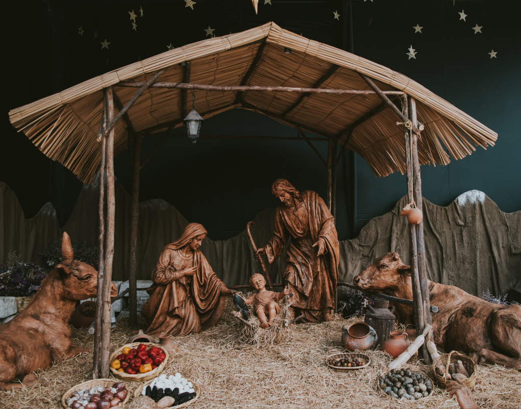 En realistisk julkrubba med figurer i brun lera och stall med stråtak.