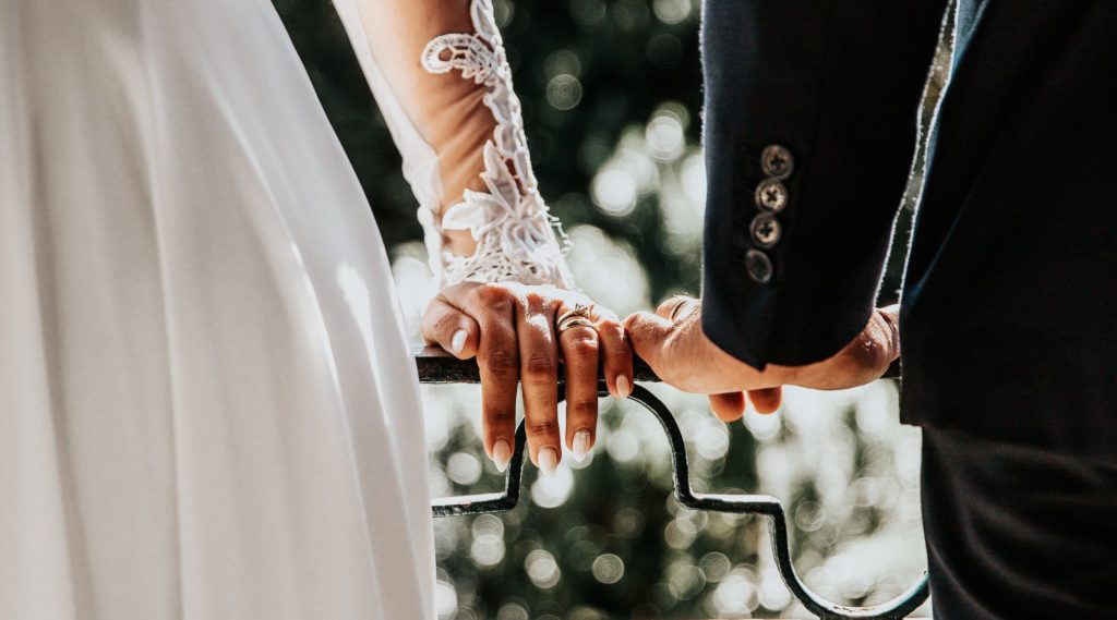 The hands of the bride and groom are holding onto the railing.
