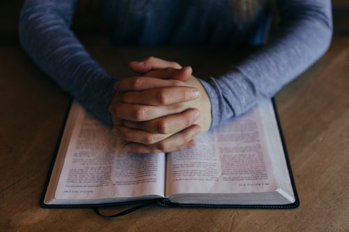 hands crossed on an open bible