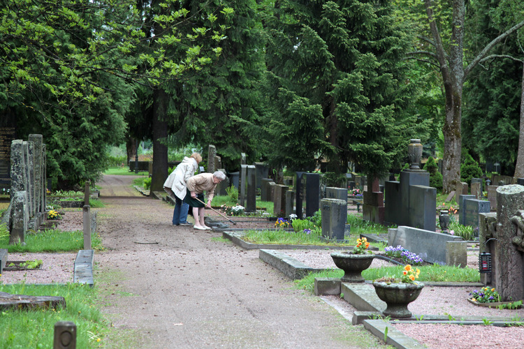 Two elderly women take care of the grave site on a summer day.