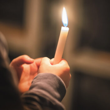Kynttilä ihmisen käsissä.