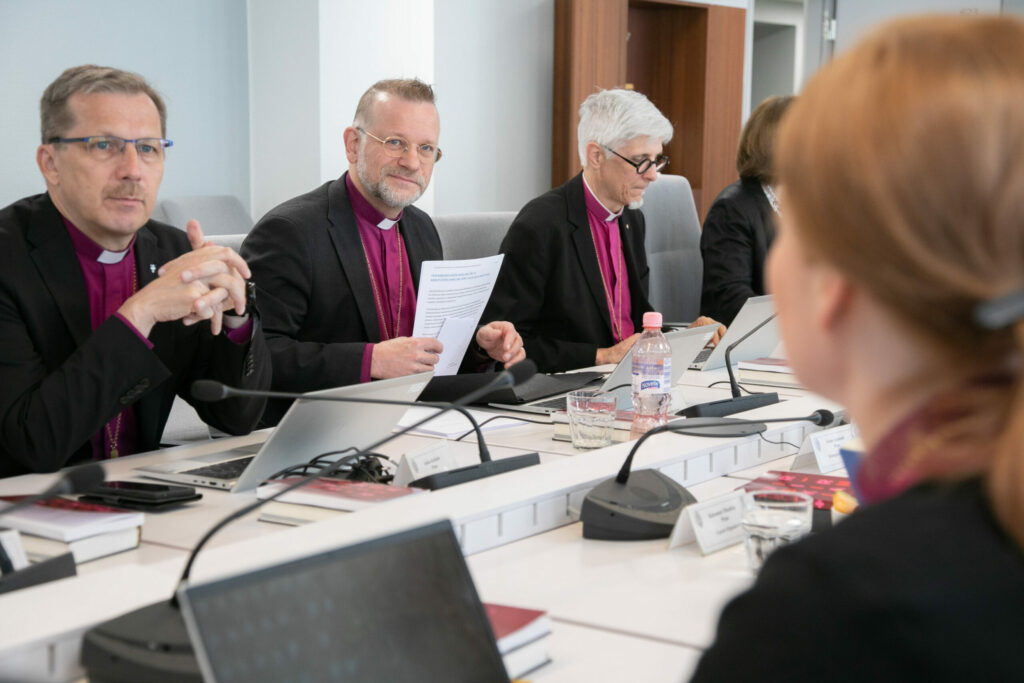 Bild från ett biskopsmöte. Några av biskoparna sitter kring ett mötesbord.