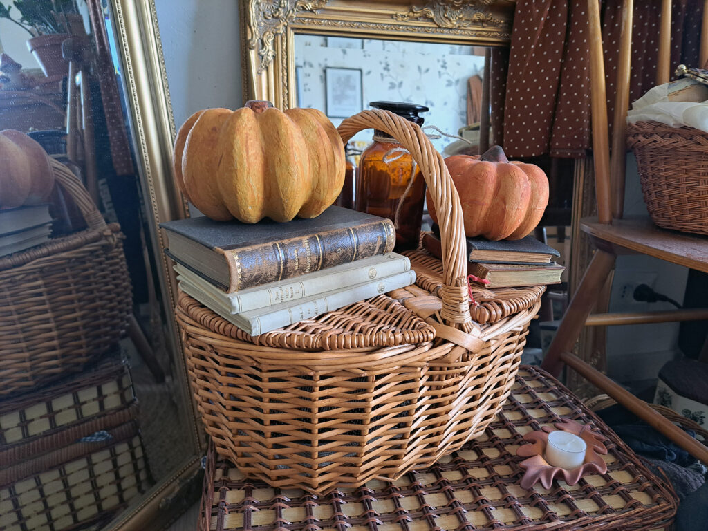 En korg med torkad frukt, böcker, spegel och andra föremål på ett bord.