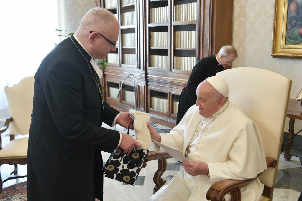 Den finländska biskopen överräcker ett par stickade vantar till påven.