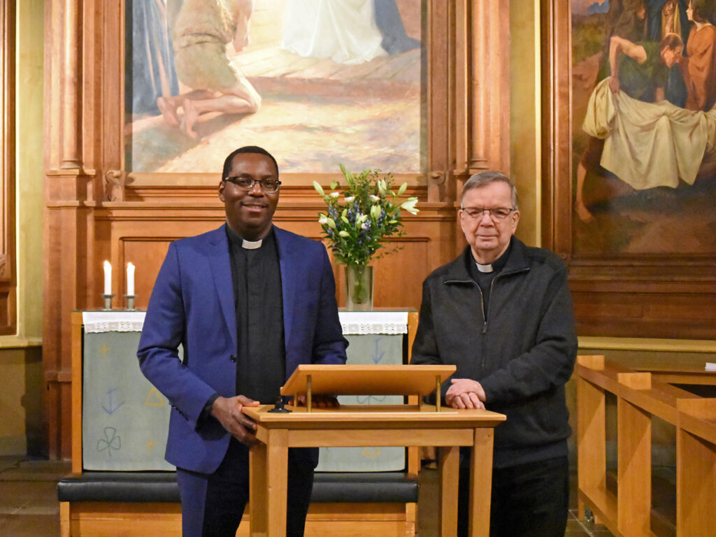Två präster står tillsammans framme i kyrkan.