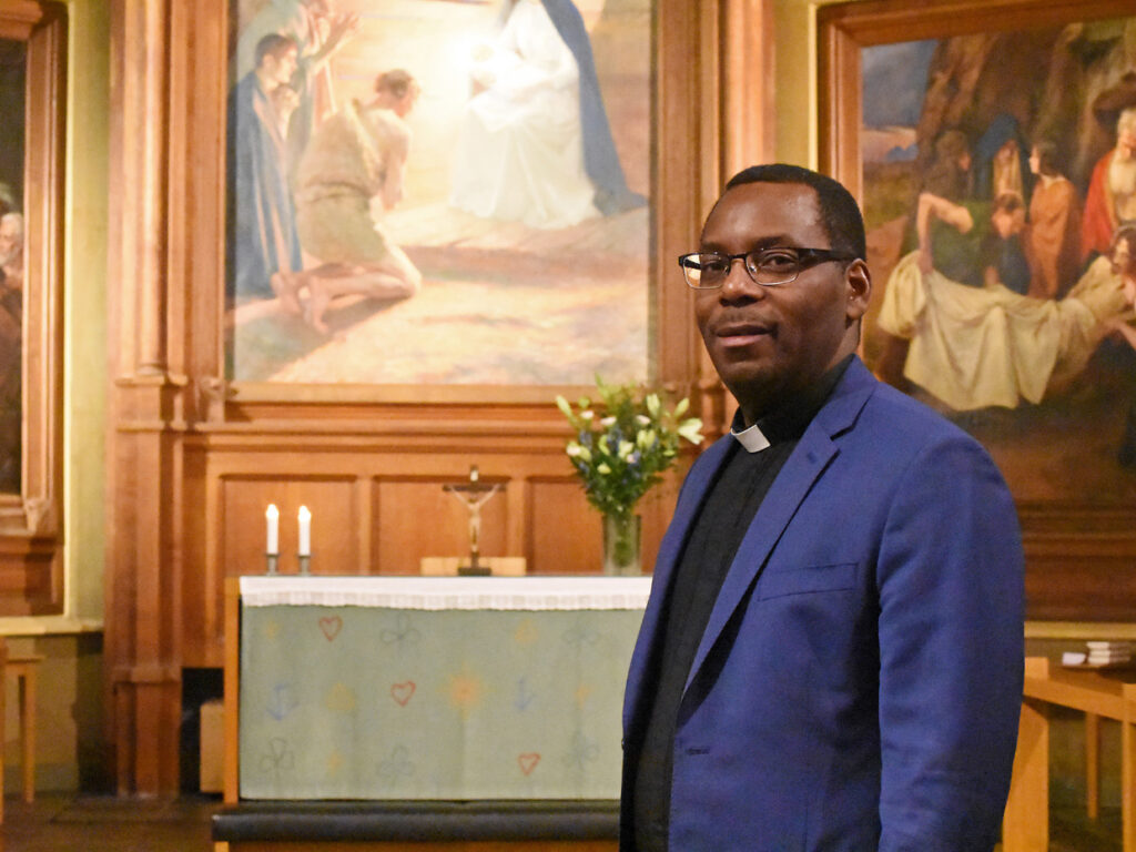 Man i prästskjorta och blå kavaj står inne i kyrka.