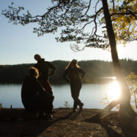 Scouter på klippstrand vid sjö.