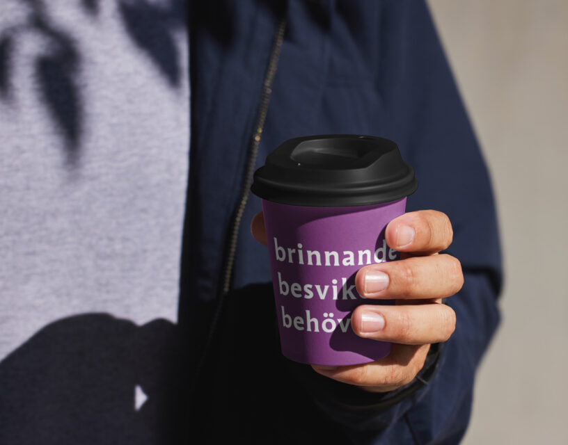 Människa håller en pappersmugg med texten "brinnande besviken behövd".