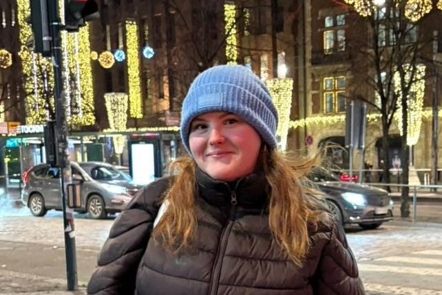 Nuori nainen kaupungin keskustassa. Taustalla jouluvalot.